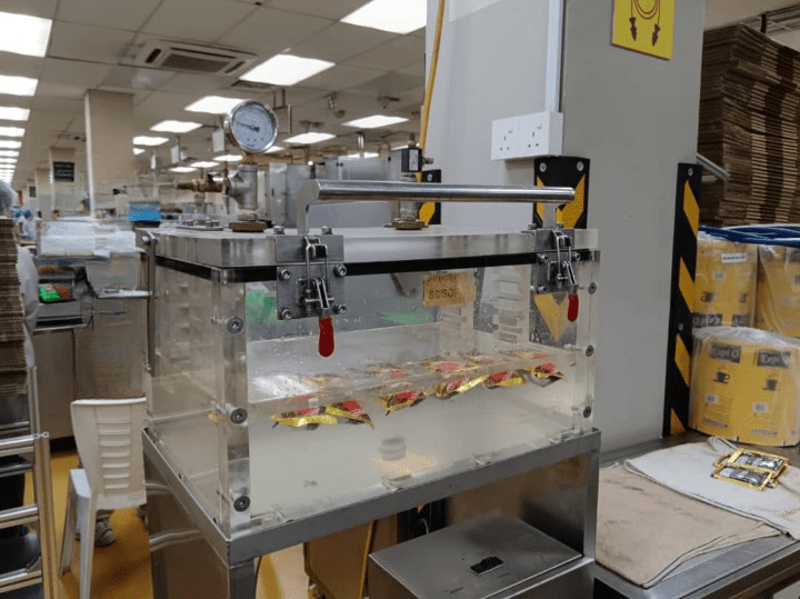 Pure Automation - An automated leak testing machine on a conveyor line, inspecting food packaging with digital sensors and status indicators.